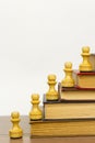 Chess pieces and books on a wooden table. Royalty Free Stock Photo