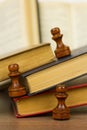 Chess pieces and books on a wooden table. Royalty Free Stock Photo