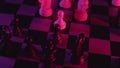 Chess pieces on a chessboard in a colorful fashion style. Studio neon light footage. Pink and purple colors. Slow tracking shot in