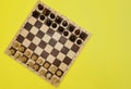 Chess pieces on a chessboard on a yellow background. Black and white figures of different designations Royalty Free Stock Photo