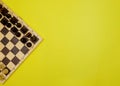 Chess pieces on a chessboard on a yellow background. Black and white figures of different designations Royalty Free Stock Photo