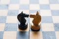 Chess pieces knights facing each other for a standoff on chessboard with blue background. Chess knights confronting each Royalty Free Stock Photo