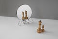 Chess pieces queen and pawn look in the mirror. Minimalistic concept of narcissistic personality disorder.