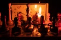 Chess pieces stand on a chessboard and clock and next to a burning candle in the dark Royalty Free Stock Photo