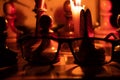 Chess pieces stand on a chessboard and clock and next to a burning candle in the dark Royalty Free Stock Photo