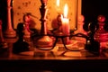 Chess pieces stand on a chessboard and clock and next to a burning candle in the dark Royalty Free Stock Photo