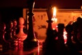 Chess pieces stand on a chessboard and clock and next to a burning candle in the dark, playing Royalty Free Stock Photo