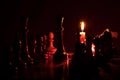 Chess pieces stand on a chessboard and next to a burning candle in the dark, playing Royalty Free Stock Photo