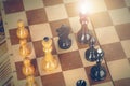 Chess pieces on a wooden chessboard against a dark background