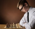 Chess Player Concentrate Thinking about Game Strategy at Chessboard. Young Boy playing boardgame over Dark Brown Studio Background Royalty Free Stock Photo