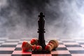 Chess queen defeats a batch of white pawns on a chessboard on a background with smoke