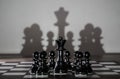 Chess queen standing on a chessboard with pawns around her. Women leadership concept