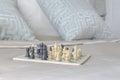 Chess set on satin bedding with light blue pillows in background Royalty Free Stock Photo