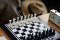 A chess set with special holes for travelers and for the blind is on the table next to the clock, sheriff`s hat and black glasses