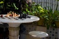 Chess wooden pieces on board in patio with green plants. Chess table in garden. Outdoor stone chessboard with figures. Royalty Free Stock Photo