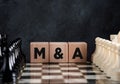 Chessboard with chess pieces and wooden blocks with the word mergers and acquisitions Royalty Free Stock Photo