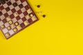 Chessboard with chesses on yellow background, top view