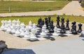 Chessboard with huge black and white chess pieces for outdoor play on  beach. Royalty Free Stock Photo