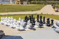 Chessboard with huge black and white chess pieces for outdoor play on  beach. Royalty Free Stock Photo