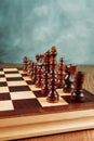 A chessboard made of wood with chess pieces placed on it stands on a table