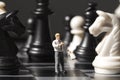 Chessman and chess figures on game board. Playing chess with miniature doll macro photo. Royalty Free Stock Photo
