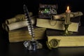 The chest with jewelry, old documents in scrolls and books, a burning candle and a compass on a black background Royalty Free Stock Photo