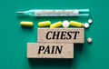 CHEST PAIN - text on wooden bars on the background of a thermometer and pills