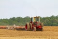 A red six wheel International 1586 tractor with cabin is plowing a blank agricultural field Royalty Free Stock Photo