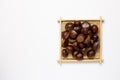 Chestnuts in wooden tray on white background. Autumn and winter snacks Royalty Free Stock Photo