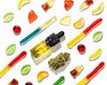 Among Chewing marmalade a dried cannabis bud and bottles of marijuana seed oil lie in a pattern on a white background