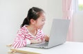 Chherful Asian little child girl sitting at desk and using laptop computer stay at home Royalty Free Stock Photo