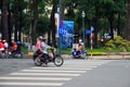 Ho Chi Minh city, Vietnam - December 2018: motorbike with tow people stopped on the crosswalk near the park.