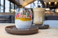 Chia pudding with mango puree, oats flakes and fresh strawberries and cup with cappuccino on wooden table in cafe Royalty Free Stock Photo