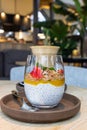 Chia pudding with mango puree, oats flakes and fresh strawberries and cup with cappuccino on wooden table in cafe Royalty Free Stock Photo