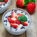 Chia seed pudding with strawberries, almond and chocolate cookie crumbs, on wooden table, square format Royalty Free Stock Photo