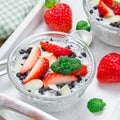 Chia seed pudding with strawberries, almond and chocolate cookie crumbs, in wooden tray, square format Royalty Free Stock Photo