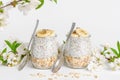 Chia seed pudding with yogurt and oats on white background decorated with flowers. Superfood concept.