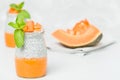 Chia seeds pudding with pumpkin puree in beautiful glasses with green mint leaves and cut fresh ripe orange vegetable. Royalty Free Stock Photo