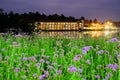 Lakeside buildings with flower beds in the foreground at night