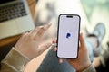 Close-up image of a woman\'s hand holding a smartphone with PayPal logo on screen