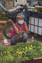 CHIANG MAI, THAILAND - JULY 5, 2021: A seller of morning glory and lemon wearing masks is sitting on a stall in the market in