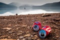 Chiang Mai/ Thailand - May 16, 2019: Two distorted empty Coca-cola cans dumped on the beach full of gravels and pebbles with backg