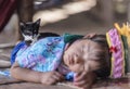 Long neck tribal girl sleeping on floor and her pet cat sitting on her back, Chiang Mai, Thailand