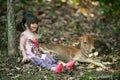 Cute girl sits under a tree in the forest with a friendly calf. The two are friends