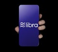 Chiangmai, Thailand - June 27th, 2019: Close up of young woman hand holding Smartphone with Libra logo isolate on black background