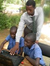 Teacher teaching students to use a computer.