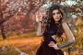 Chic dark-haired tattooed young woman wearing lace dress and black jewel crown with veil standing in the autumn garden Royalty Free Stock Photo
