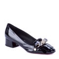 Chic female black patent leather shoe with low flare heel and front embellishment on a white background