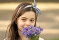 Chic floral look. Small child hold blue flowers outdoors. Beauty look of cute girl. Fashion look of little model