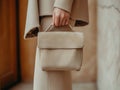 Chic and minimalist beige leather handbag complementing a modern tailored outfit. Royalty Free Stock Photo